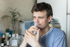 Portrait Of Young Man Inhaling Through Inhaler Mask